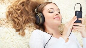 16466483 - smiling woman lying on carpet and listening to music