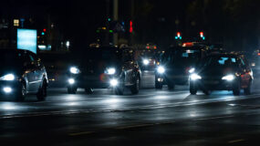 Multiple vehicles on a city street at night with their headlights on
